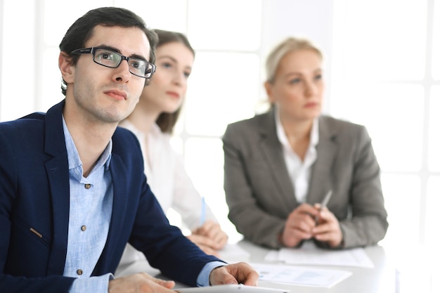 Groep zakenmensen die vragen bespreken tijdens een bijeenkomst in een modern kantoor. headshot van zakenman bij onderhandeling. teamwork, partnerschap en bedrijfsconcept.