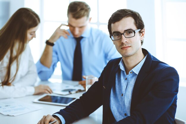 Groep zakenmensen die vragen bespreken tijdens een bijeenkomst in een modern kantoor. Headshot van zakenman bij onderhandeling. Teamwork, partnerschap en bedrijfsconcept.