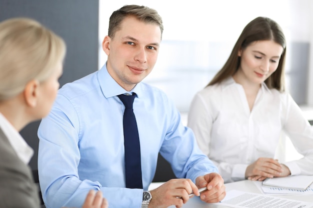 Groep zakenmensen die vragen bespreken tijdens een bijeenkomst in een modern kantoor. Headshot van zakenman bij onderhandeling. Teamwork, partnerschap en bedrijfsconcept.