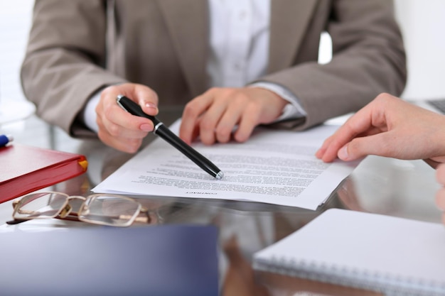 Groep zakenmensen en advocaten die contractpapieren bespreken die van dichtbij aan tafel zitten