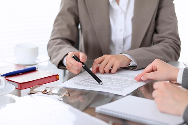 Groep zakenmensen en advocaten die contractpapieren bespreken die van dichtbij aan tafel zitten