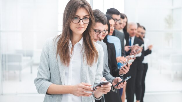 Groep zakenmensen met smartphones die op een rij staan