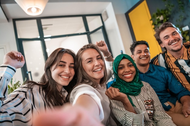 Groep zakenmensen tijdens een pauze van het werk die selfie-foto's maken terwijl ze genieten van vrije tijd in de ontspanningsruimte bij een modern open startkantoor. Selectieve aandacht. Foto van hoge kwaliteit