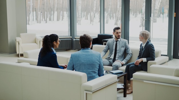 Groep zakenpartners die een overeenkomst bespreken terwijl ze op de bank zitten in een moderne kantoorzaal