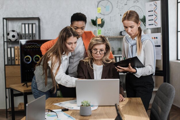 Groep zelfverzekerde hooggeschoolde multiraciale zakenvrouwen die aan tafel staan