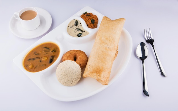 Groep zuid-indiase voedseldosa, idli of nutteloos, vada, sambar-kokoschutney en hete thee, zuid-indiase variëteitsschotel