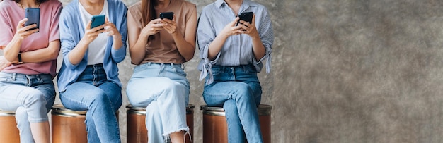 Groepen vrouwen zitten op een rij in de kamer en spelen met mobiele telefoons het concept van het gebruik van een smartphone-communicatietool om sociale media af te spelen en berichten te verzenden om met mensen te praten via applicaties