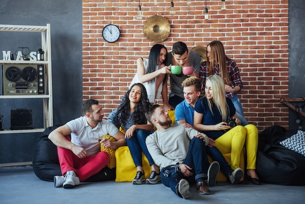 Groepsportret van multi-etnische jongens en meisjes met kleurrijke modieuze kleding met vriend die zich voordeed op een bakstenen muur, stedelijke stijl mensen plezier, s over jeugd saamhorigheid levensstijl