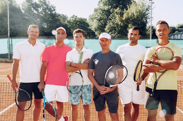 Groepsportret van zes mannelijke tennissers die zich op de baan bevinden