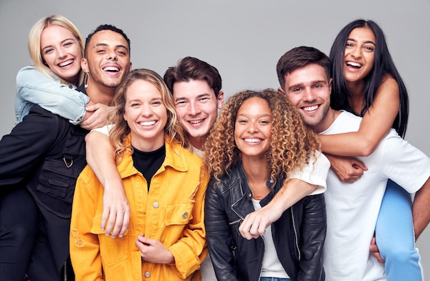 Groepsstudio-opname van jonge multiculturele vrienden die elkaar meeliften en glimlachen naar de camera