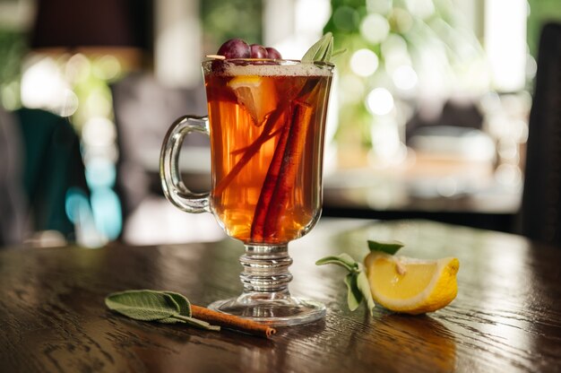 Grog. Hot drink for winter or autumn. Spicy tea and rum cocktail with lemon, grape, cinnamon and cloves.