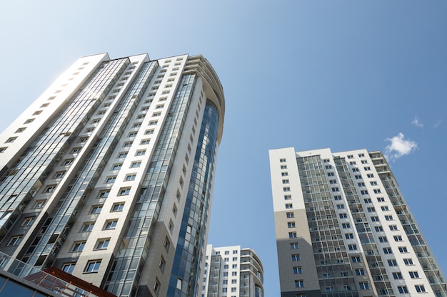 Grond diagonale weergave van hoog modern luxe betegeld flatgebouw op blauwe hemelachtergrond.