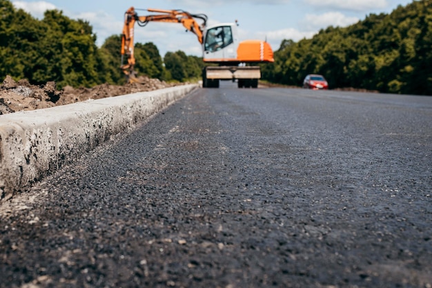 Grondgraafmachine aan het werk langs de weg Wegendienst repareert de snelweg