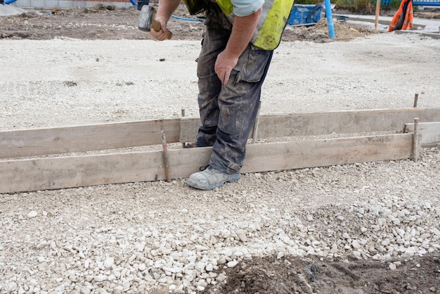 Grondwerker maakt luik voor beton om een basis te vormen voor stoeprand met behulp van steigerplanken