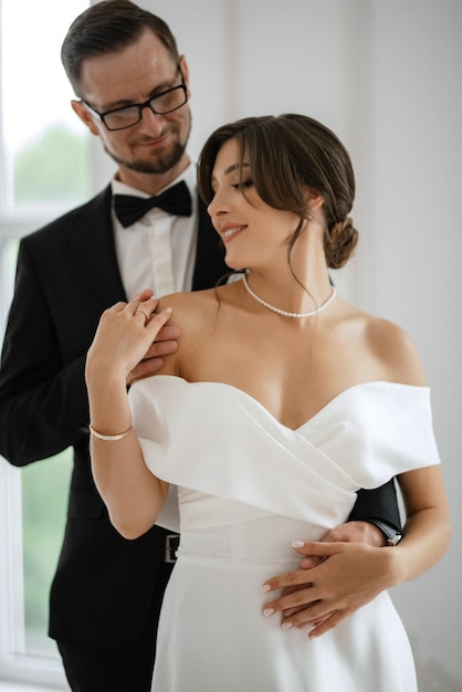 Groom in a black suit tie and the bride in a bright studio