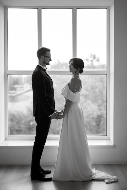 Groom in a black suit tie and the bride in a bright studio