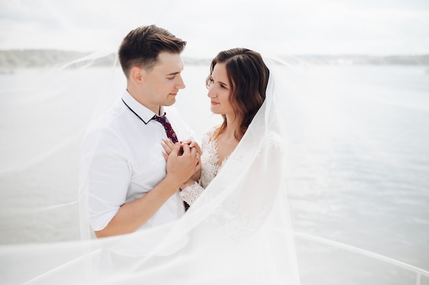 Groom in black suit with bride in long white dress ride on a large white yacht together