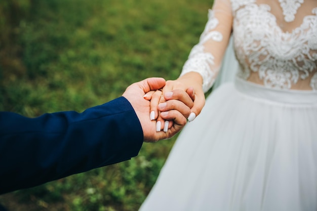 Groom and bride are holding hands Happy wedding couple photo Romantic photoshoot White dress with long sleeves Lace veil