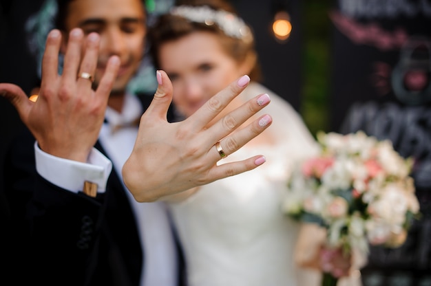 Photo groom and bride showing wedding rings on their fingers