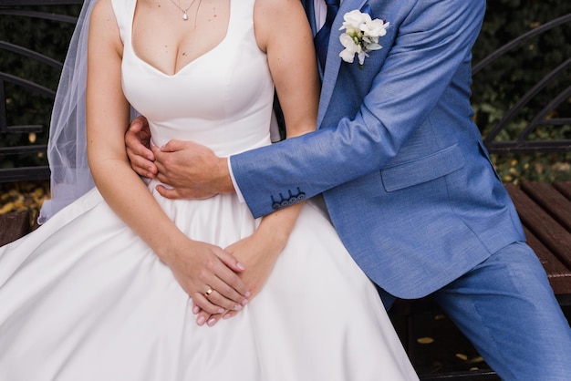 The groom and the bride sit on a bench in the park