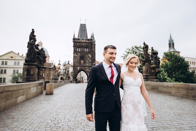 Groom and bride walk on the Charles Bridge