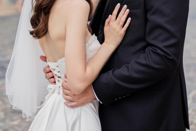 The groom and the bride in a wedding dress stand together on the street