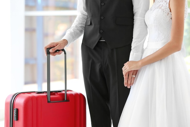 Groom and bride with big suitcase indoors