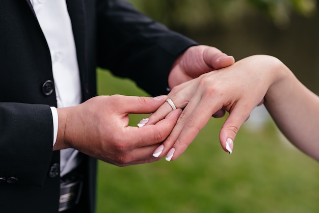 The groom dresses the bride's wedding ring on hand.