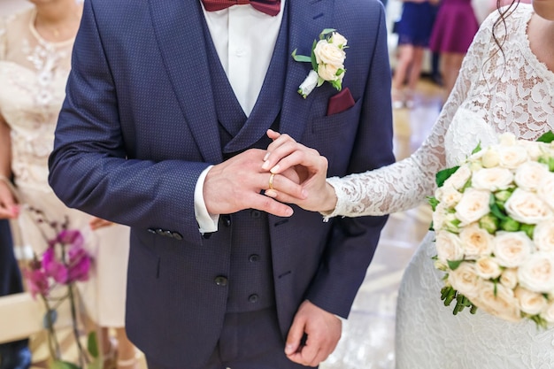 Groom embraces the bride with wedding bouquet with violet rose groom dresses an engagement ring to the bride newlyweds exchange wedding rings