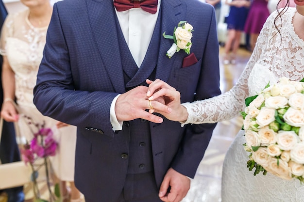 Groom embraces the bride with wedding bouquet with violet rose groom dresses an engagement ring to the bride newlyweds exchange wedding rings