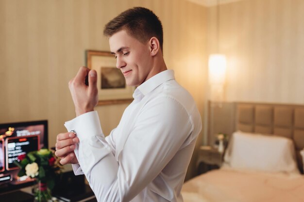 The groom fastens the sleeves on his shirt groom preparing for the wedding