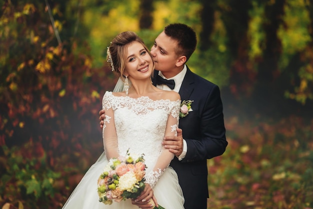 The groom gently kisses the bride on the cheek Autumn mystical forest