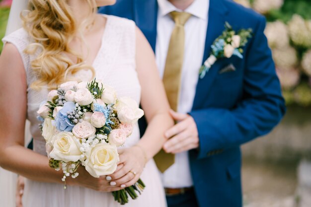 The groom gently touches the brides hand holding the bouquet during the wedding ceremony