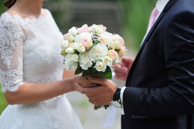 Groom gives the bride close-up beautiful wedding bouquet. For walk in the park.