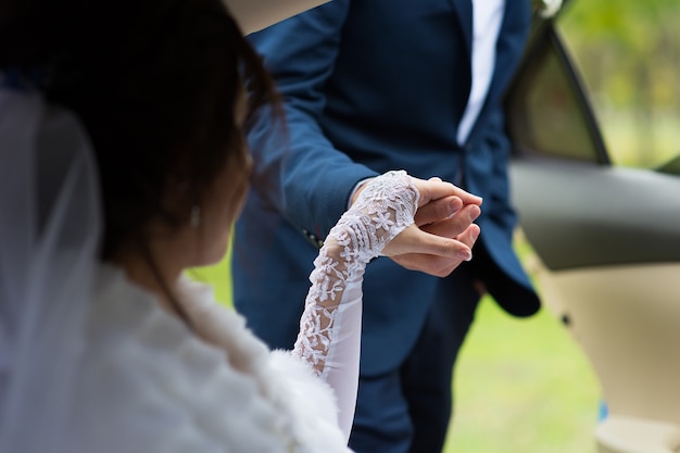 The groom gives his hand to the bride in the car