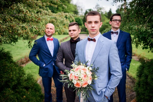 Photo groom and groomsmen look stylish posing in the green park