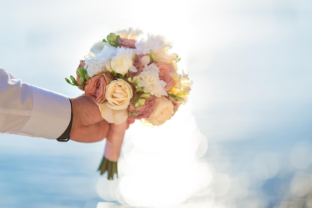 Groom holding bouquet of flowers on the beach Sea background