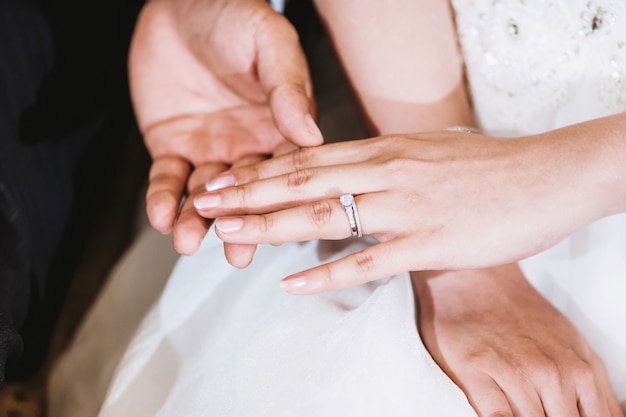 The groom holding the bride hand after put the wedding ring on her finger