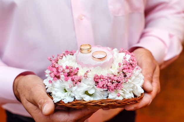 Groom holding flowers bouquet with two wedding rings