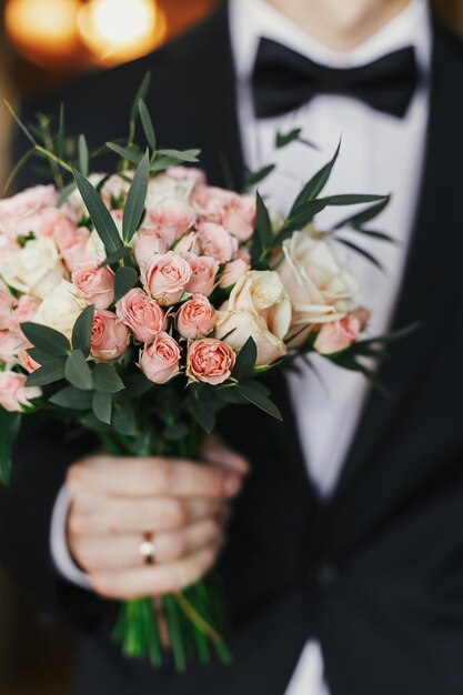 Groom holding stylish bouquet with roses and eucalyptus morning preparations before wedding day groom waiting for his bride