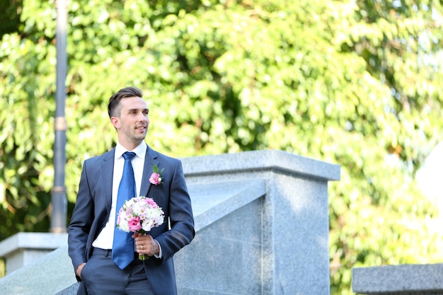 Groom holding wedding bouquet outdoors