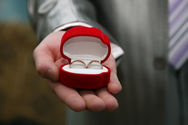 The groom holds a box with gold wedding rings close up