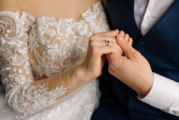 新郎はリングで手で花嫁を保持します。愛の新婚夫婦の美しいエレガントなカップル。結婚式のコンセプトです。閉じる。