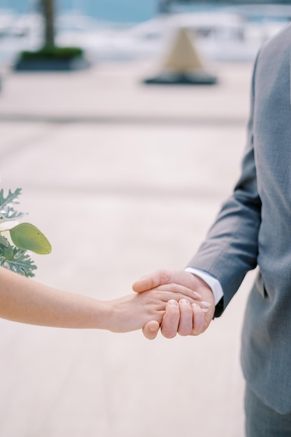 Groom holds bride hand with a bouquet Cropped Faceless