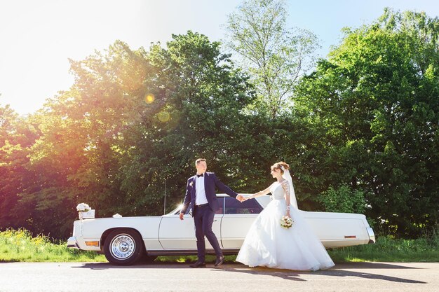 Foto lo sposo tiene la mano della sposa e guarda i novelli sposi.