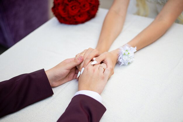 The groom holds the hands of the bride