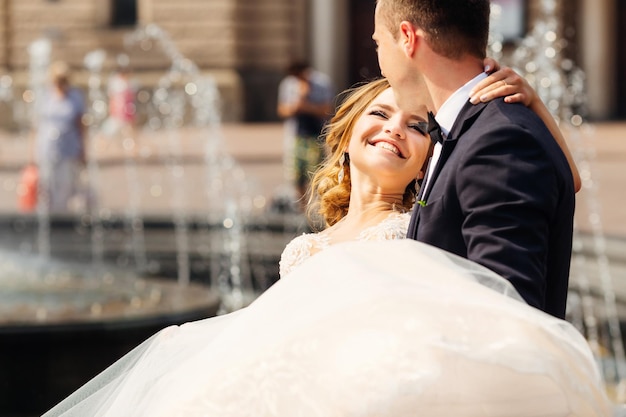 The groom holds his beloved bride in his arms