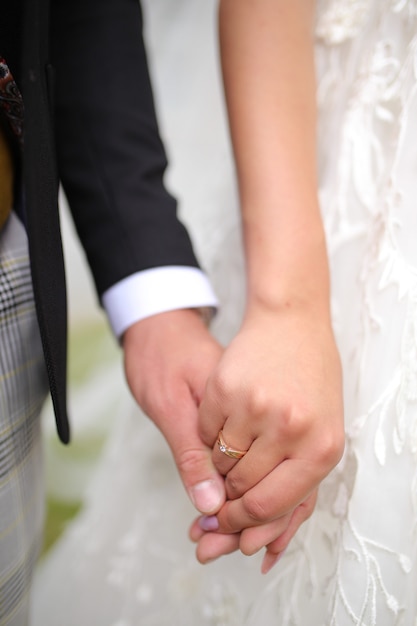 The groom holds in his hand the bride's hand on the finger of a gold wedding ring