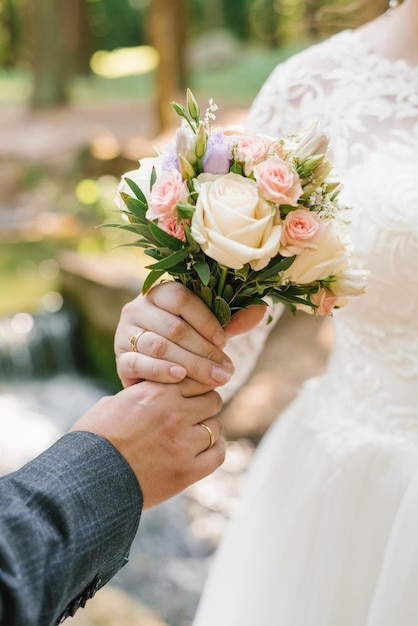 新郎は新婚の手と繊細な花束のクローズアップ花嫁に結婚式の花束を差し出します