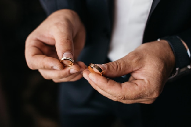 groom holds wedding rings